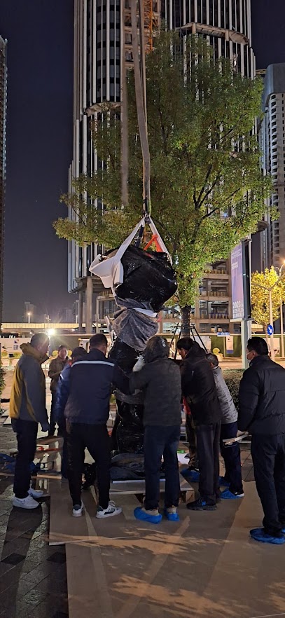 Team guiding protected cargo during a street-side lift at night